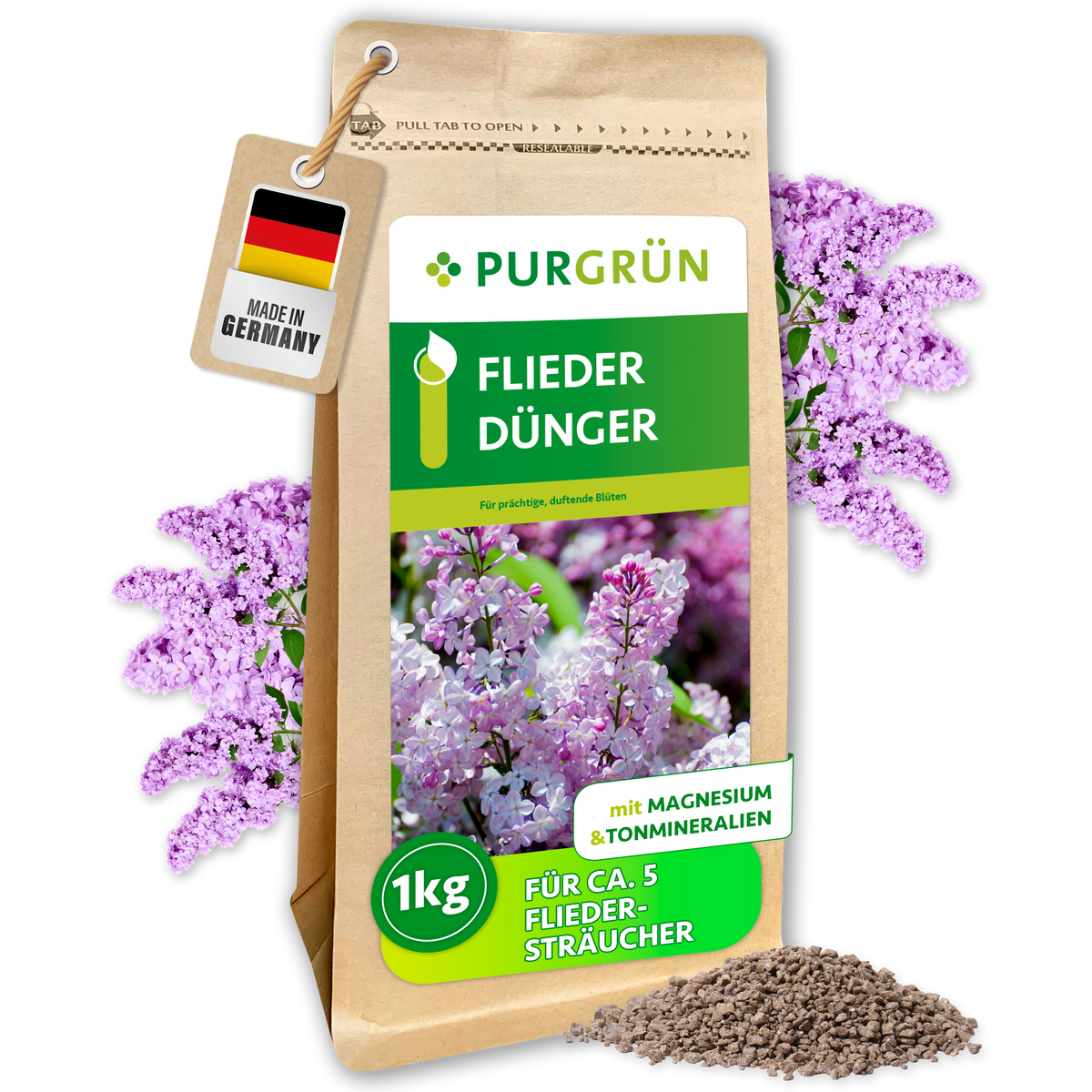 Purgrün Fliederdünger im 1-kg-Papierbeutel, umgeben von Fliederblüten und feinem Granulat; reicht für ca. 5 Fliedersträucher.