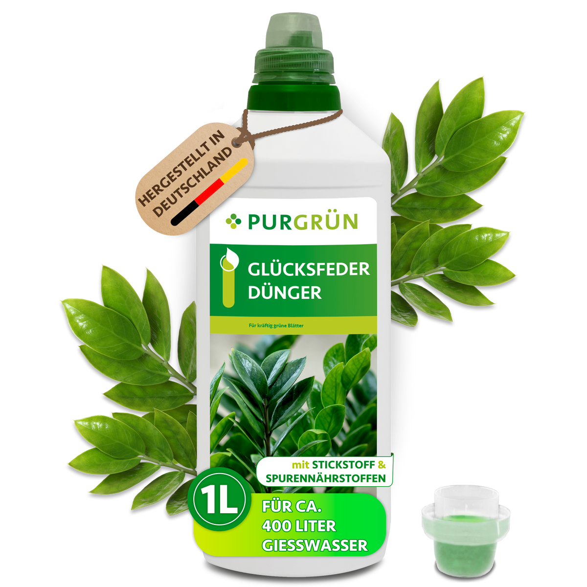 Purgrün Glücksfeder-Dünger in der 1-Liter-Flasche mit Dosierkappe, umgeben von Glücksfederblättern und dem Hinweis „Hergestellt in Deutschland“.