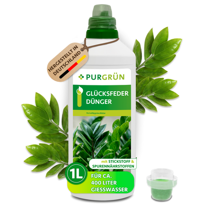Purgrün Glücksfeder-Dünger in der 1-Liter-Flasche mit Dosierkappe, umgeben von Glücksfederblättern und dem Hinweis „Hergestellt in Deutschland“.