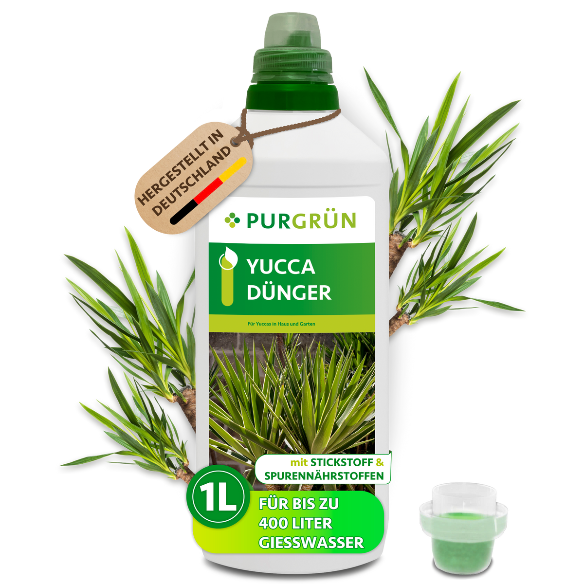 1-Liter-Flasche Purgrün Yucca-Dünger mit Dosierkappe und Anhänger „Hergestellt in Deutschland“, umgeben von Yucca-Blättern.