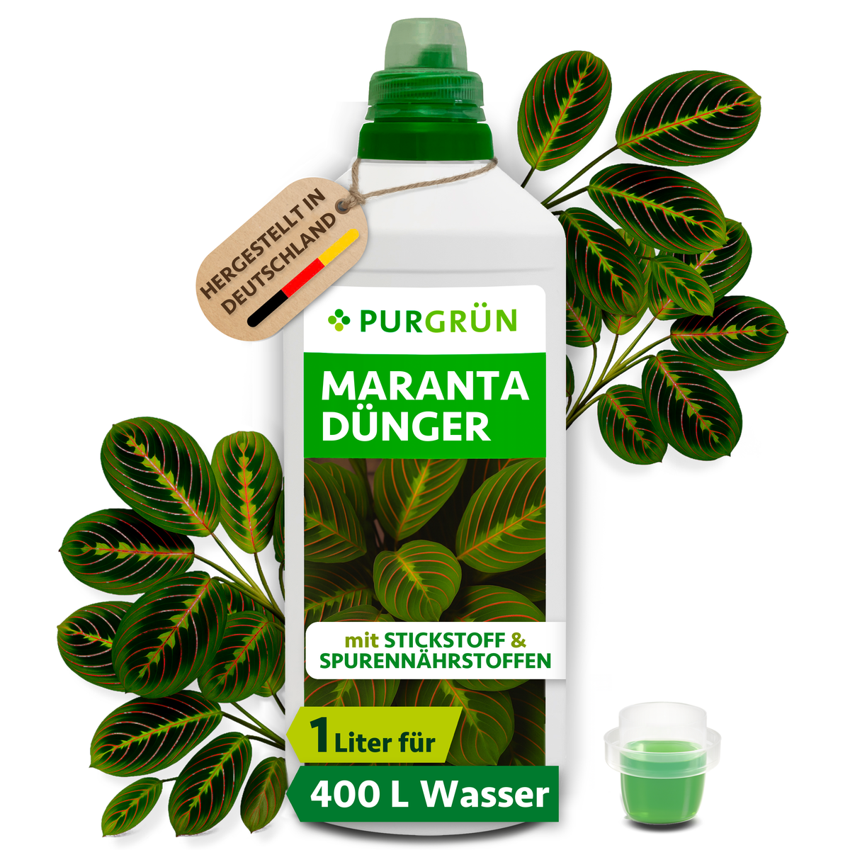 Purgrün Maranta-Dünger in der 1-Liter-Flasche mit Dosierkappe, umgeben von Maranta-Blättern und mit Anhänger „Hergestellt in Deutschland“.